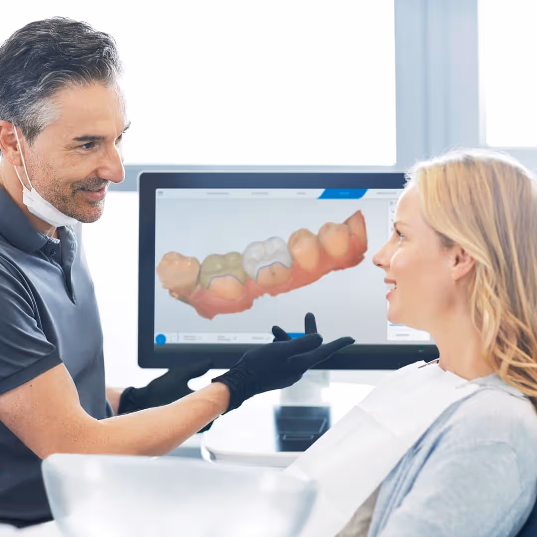 Dentist presenting a 3D digital scan of a patient's teeth on a chairside monitor before crown placement